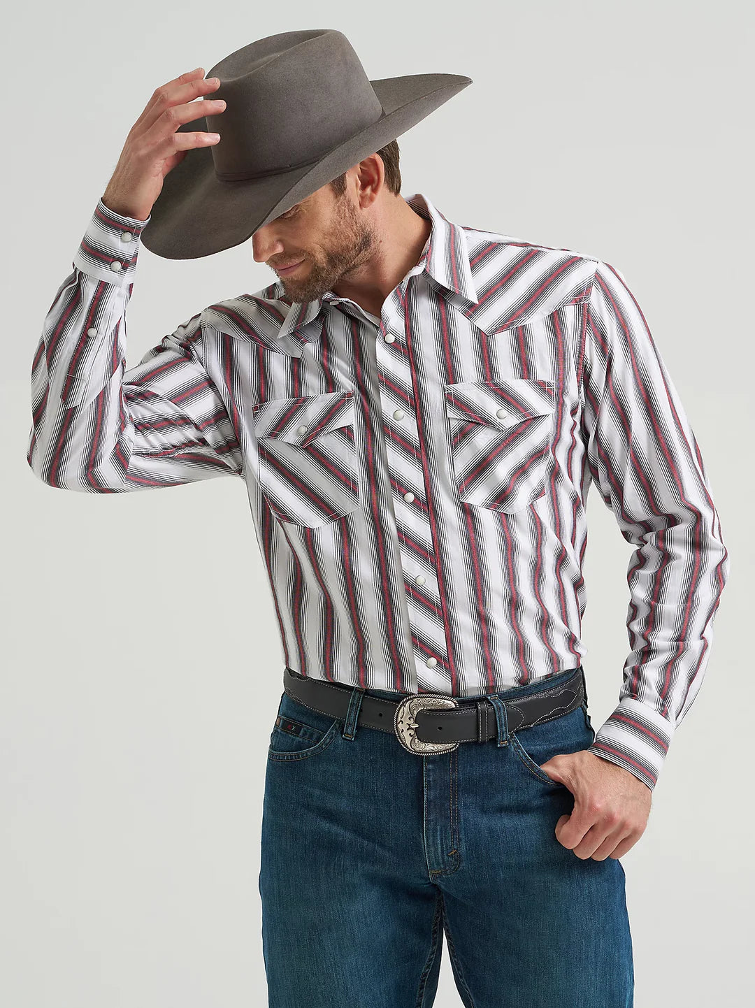 Man in striped western cowboy shirt, denim jeans, and felt hat tipping his hat
