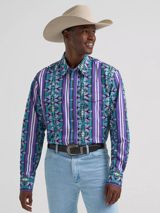 Man in a purple and turquoise western shirt, cowboy hat, and light blue jeans