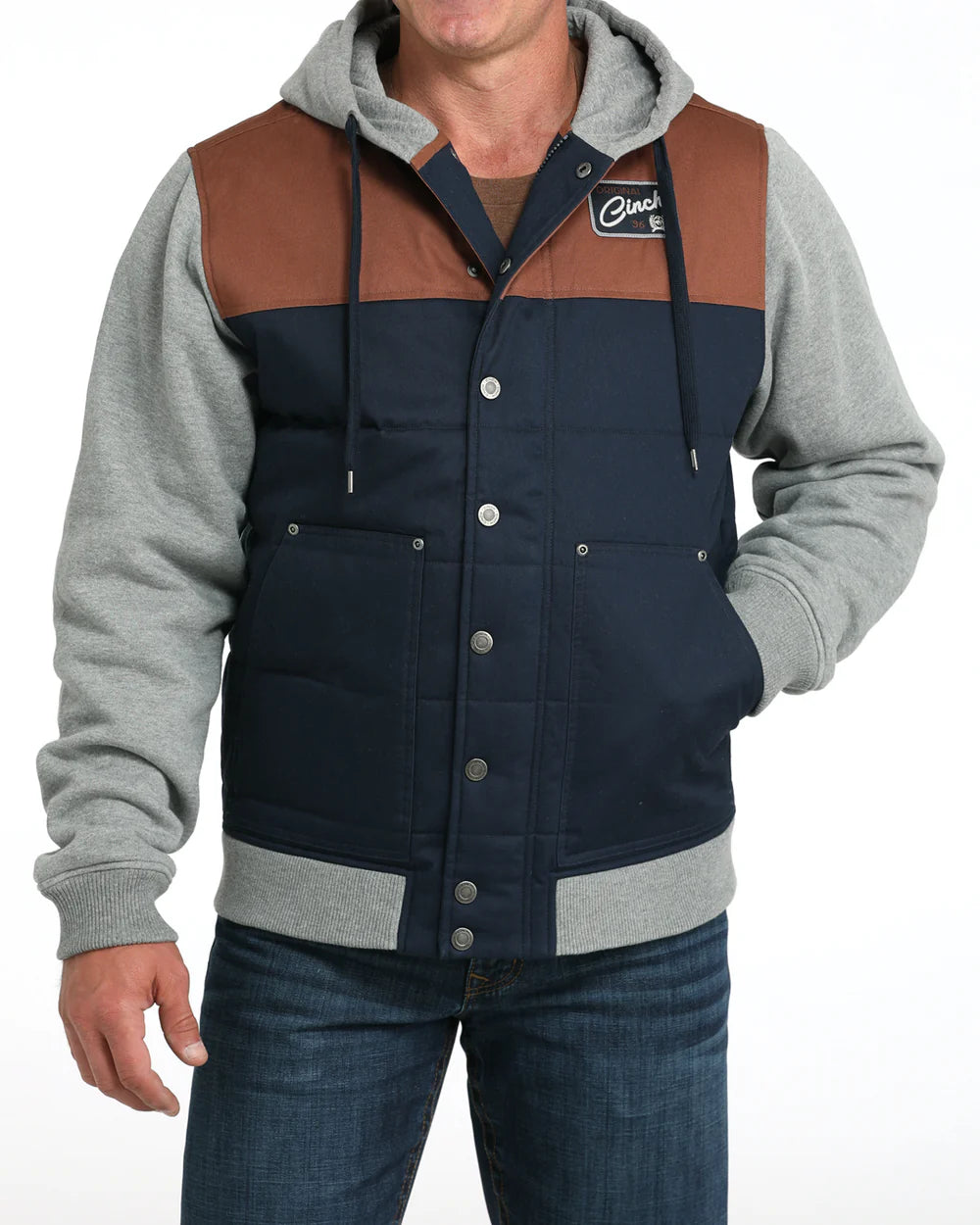 Man wearing a navy and brown insulated jacket with grey hoodie sleeves and front buttons