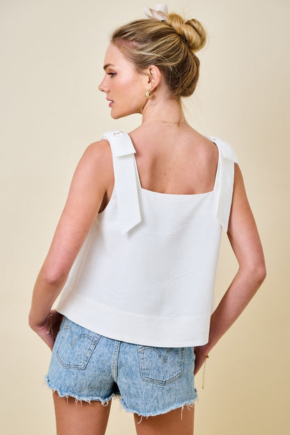 Woman wearing a white sleeveless top and denim shorts on a beige background