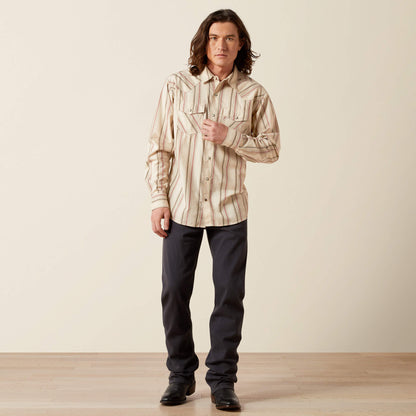 Man wearing cream striped western shirt, dark pants, and black boots standing indoors