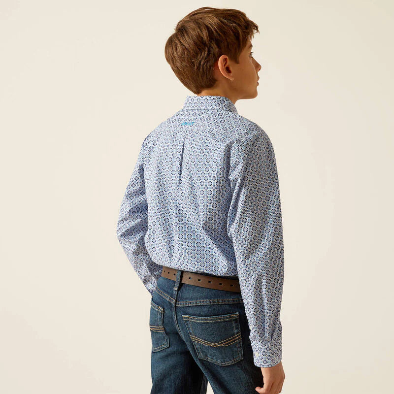 Boy wearing patterned blue long sleeve shirt and dark jeans facing away