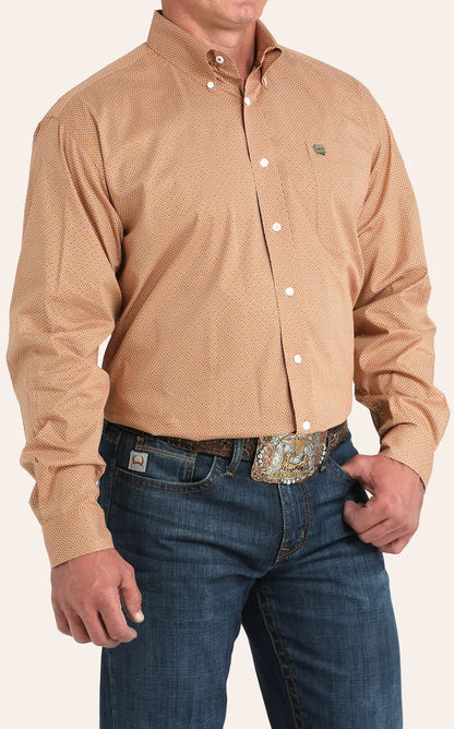 Man wearing orange geometric button-down western shirt with blue jeans and belt buckle
