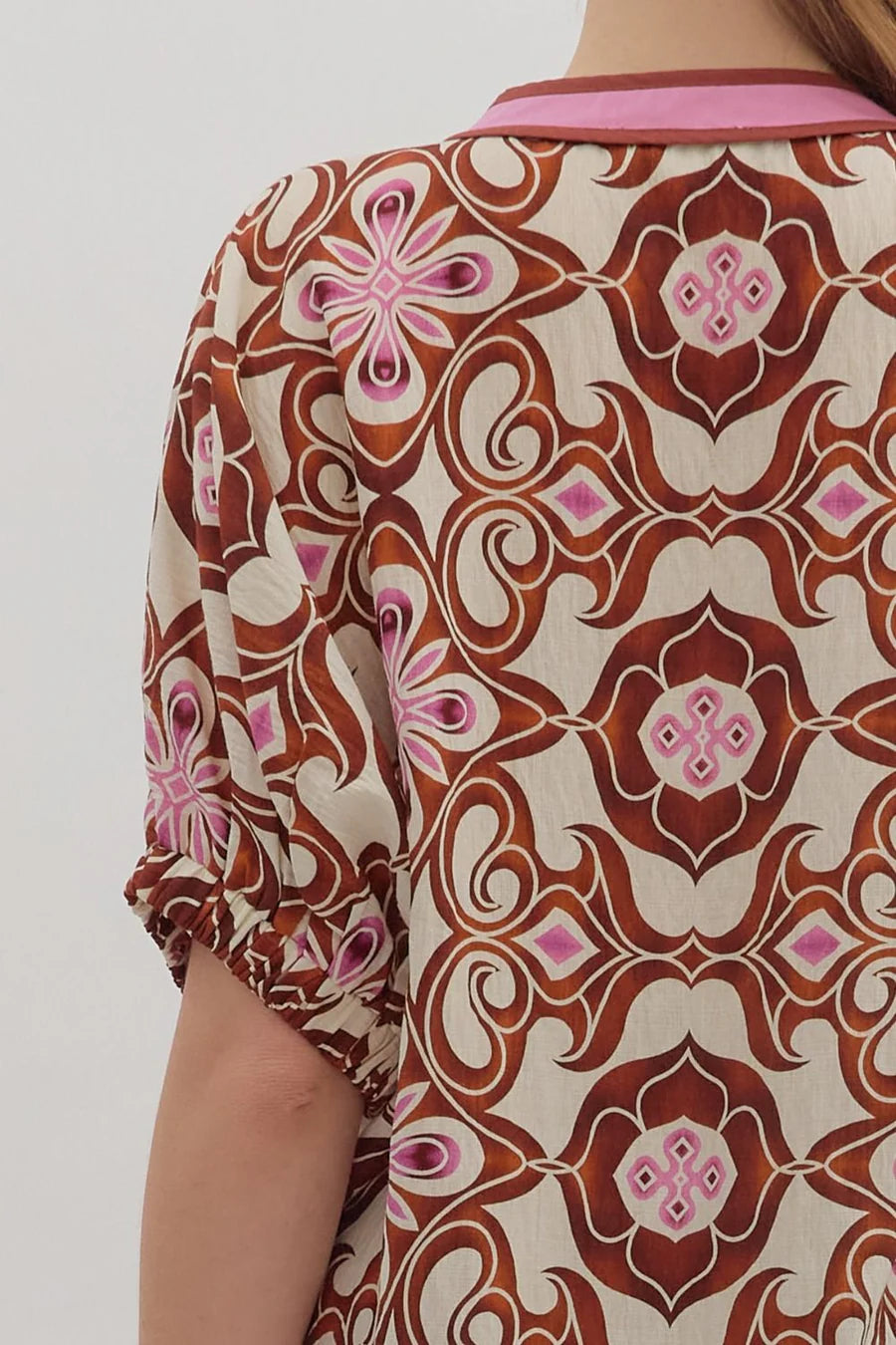 Patterned shirt with pink and brown design on a plain background
