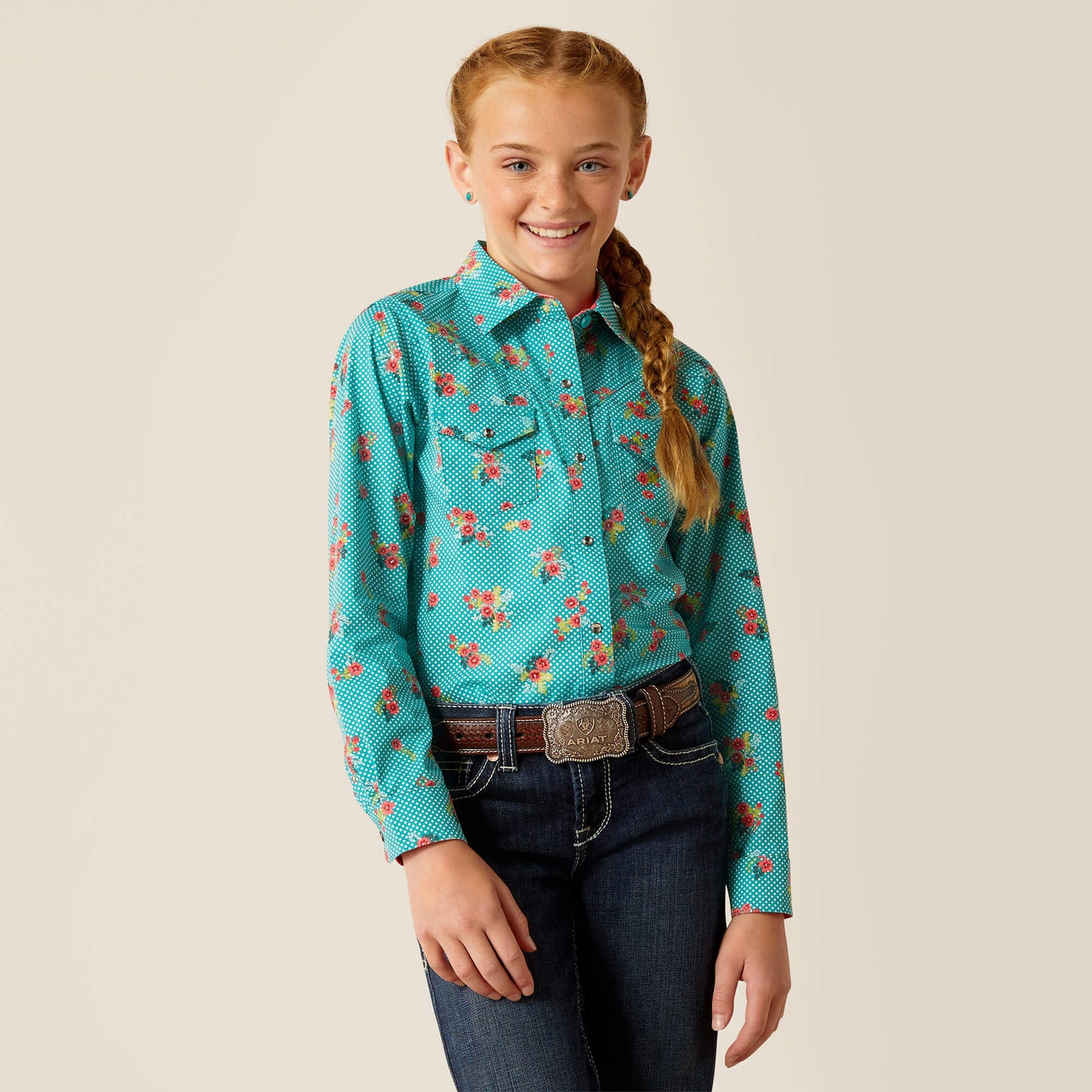 Girl wearing turquoise floral western shirt, blue jeans, brown belt with buckle