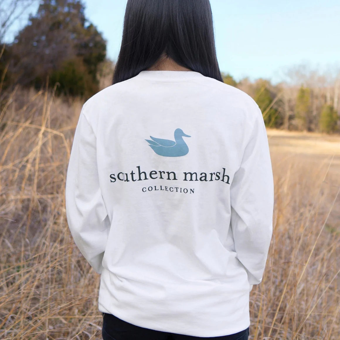 Person wearing white Southern Marsh long sleeve shirt outdoors in grassy field