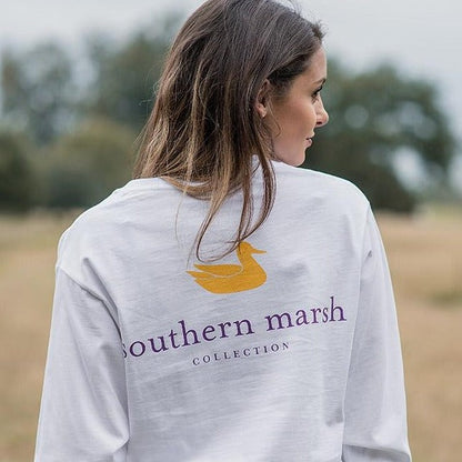 Woman outdoors wearing a white long sleeve shirt with Southern Marsh Collection logo on back