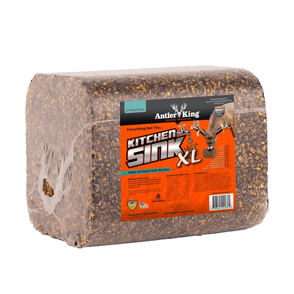 A packaged deer kick block, specifically the Antler King Kitchen Sink XL, wrapped in clear plastic with a bright orange and black label, shown on a solid white background.