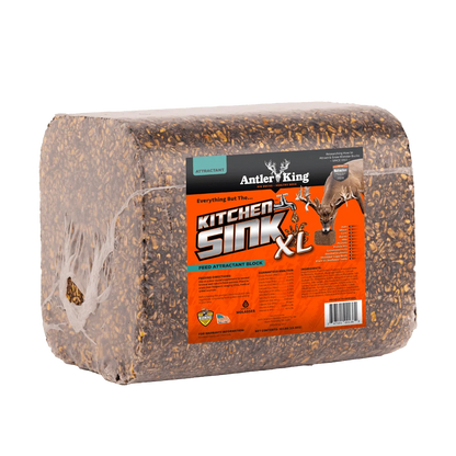 A packaged deer kick block, specifically the Antler King Kitchen Sink XL, wrapped in clear plastic with a bright orange and black label, shown on a solid white background.