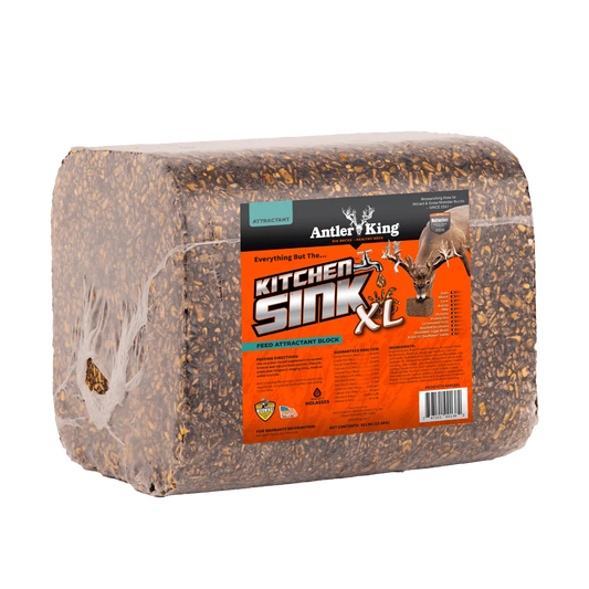 A packaged deer kick block, specifically the Antler King Kitchen Sink XL, wrapped in clear plastic with a bright orange and black label, shown on a solid white background.