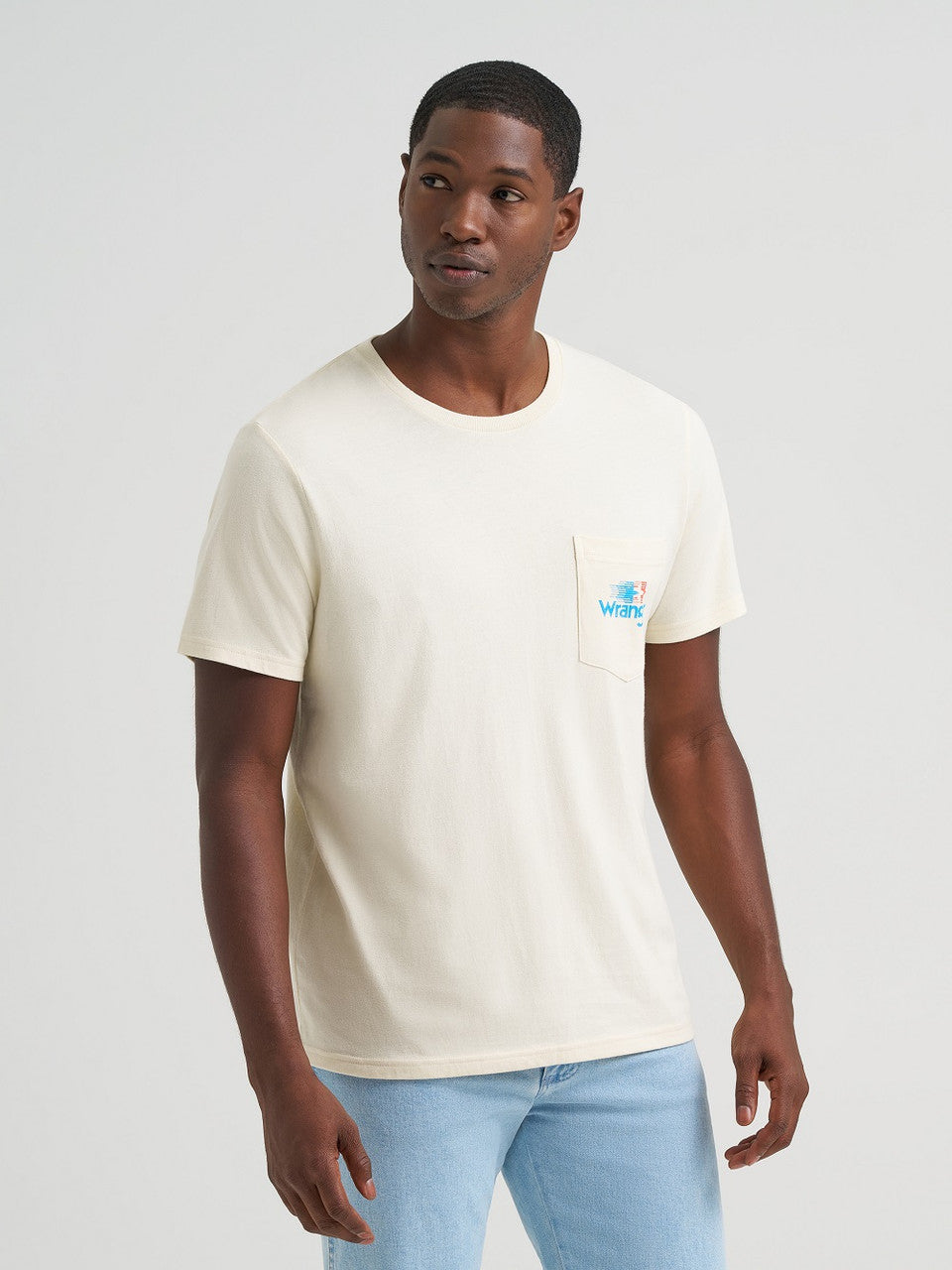 Man wearing a beige t-shirt with a logo on a plain background