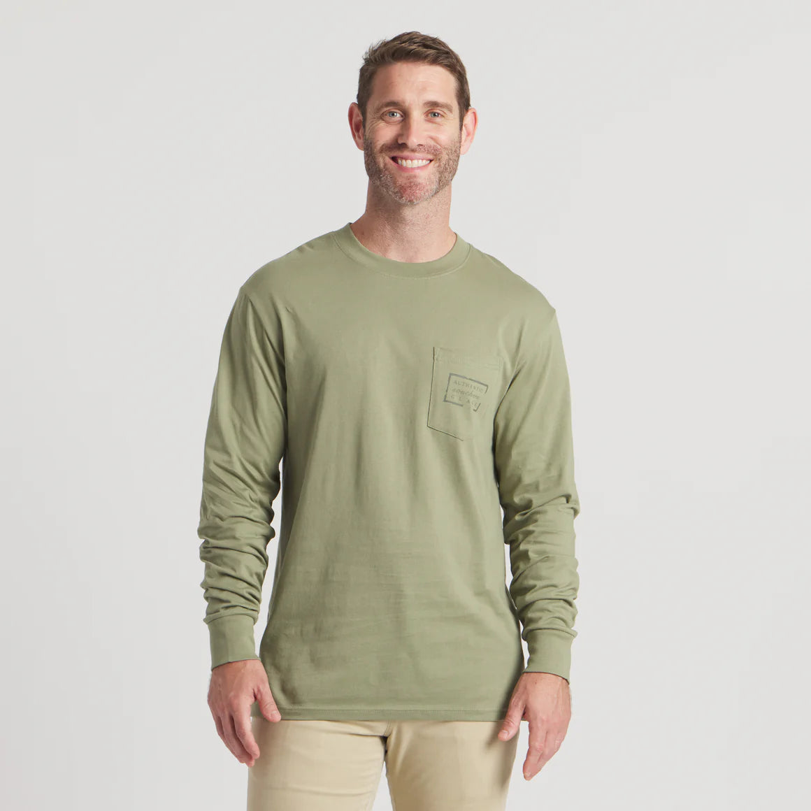 Smiling man wearing light olive green long sleeve shirt with chest pocket, beige pants