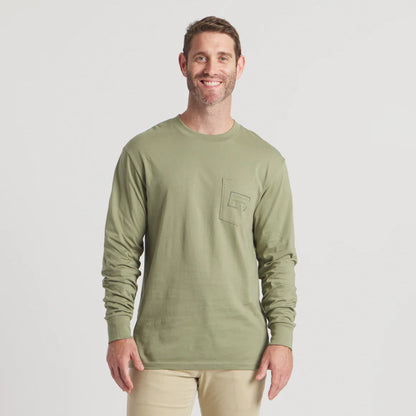 Smiling man wearing light olive green long sleeve shirt with chest pocket, beige pants