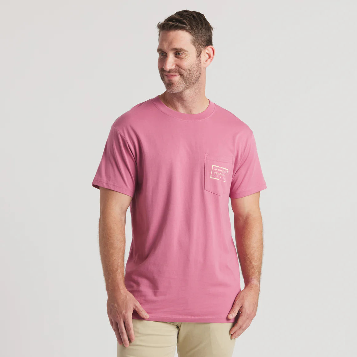 Man wearing pink short sleeve pocket t-shirt and khaki pants, front view