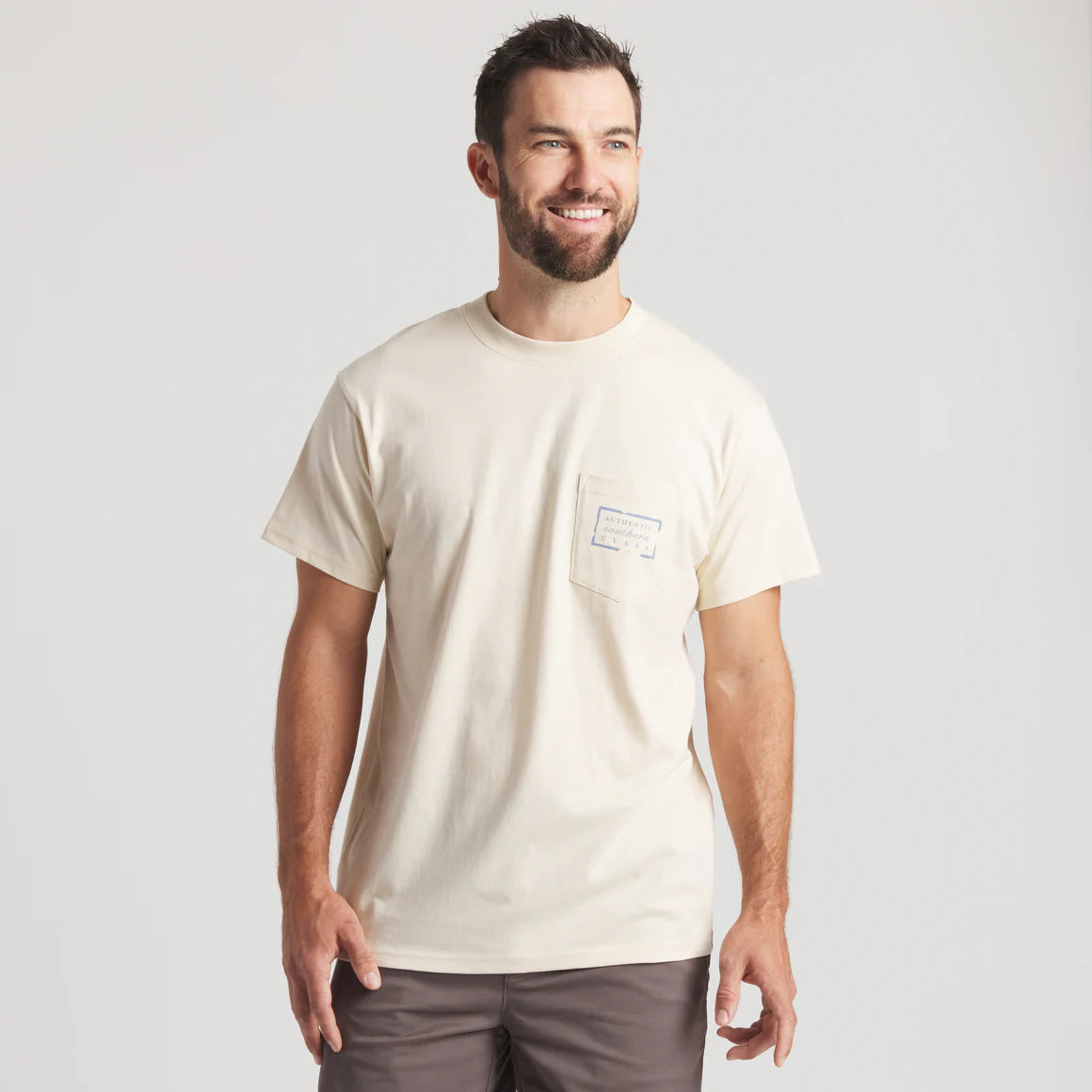 Man wearing cream short sleeve t-shirt with chest pocket and label, casual outfit