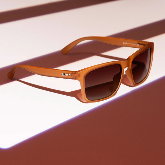 Brown sunglasses with a brand logo on a light background