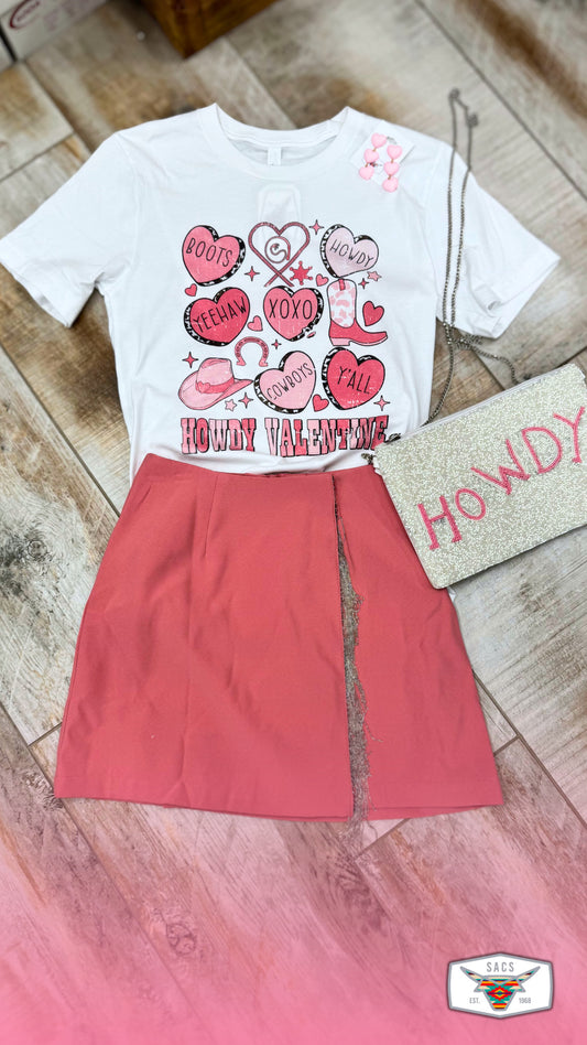 Western Valentine graphic tee with red skirt and glitter HOWDY clutch on wood floor