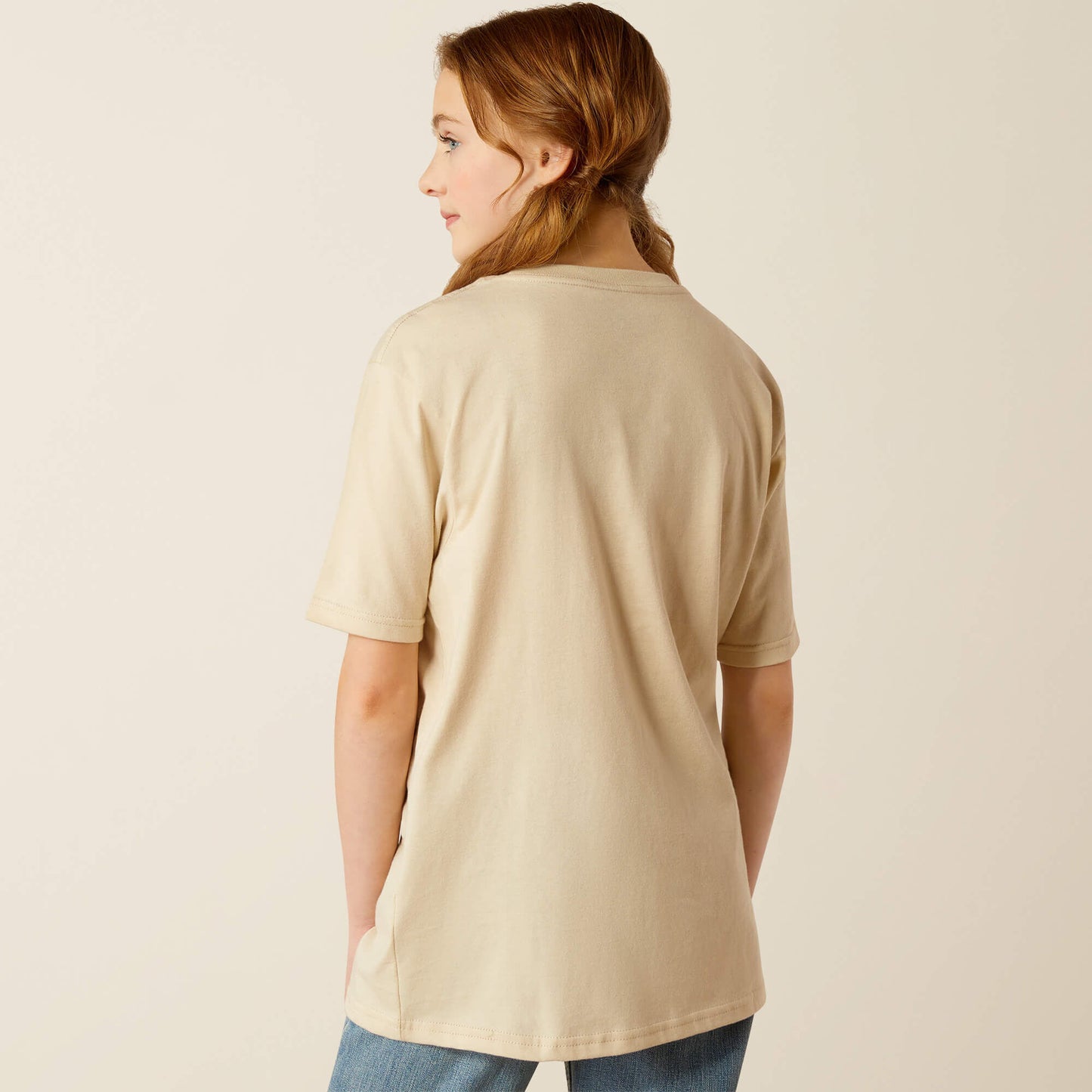 Woman wearing beige short sleeve t-shirt and jeans, shown from the back, neutral background