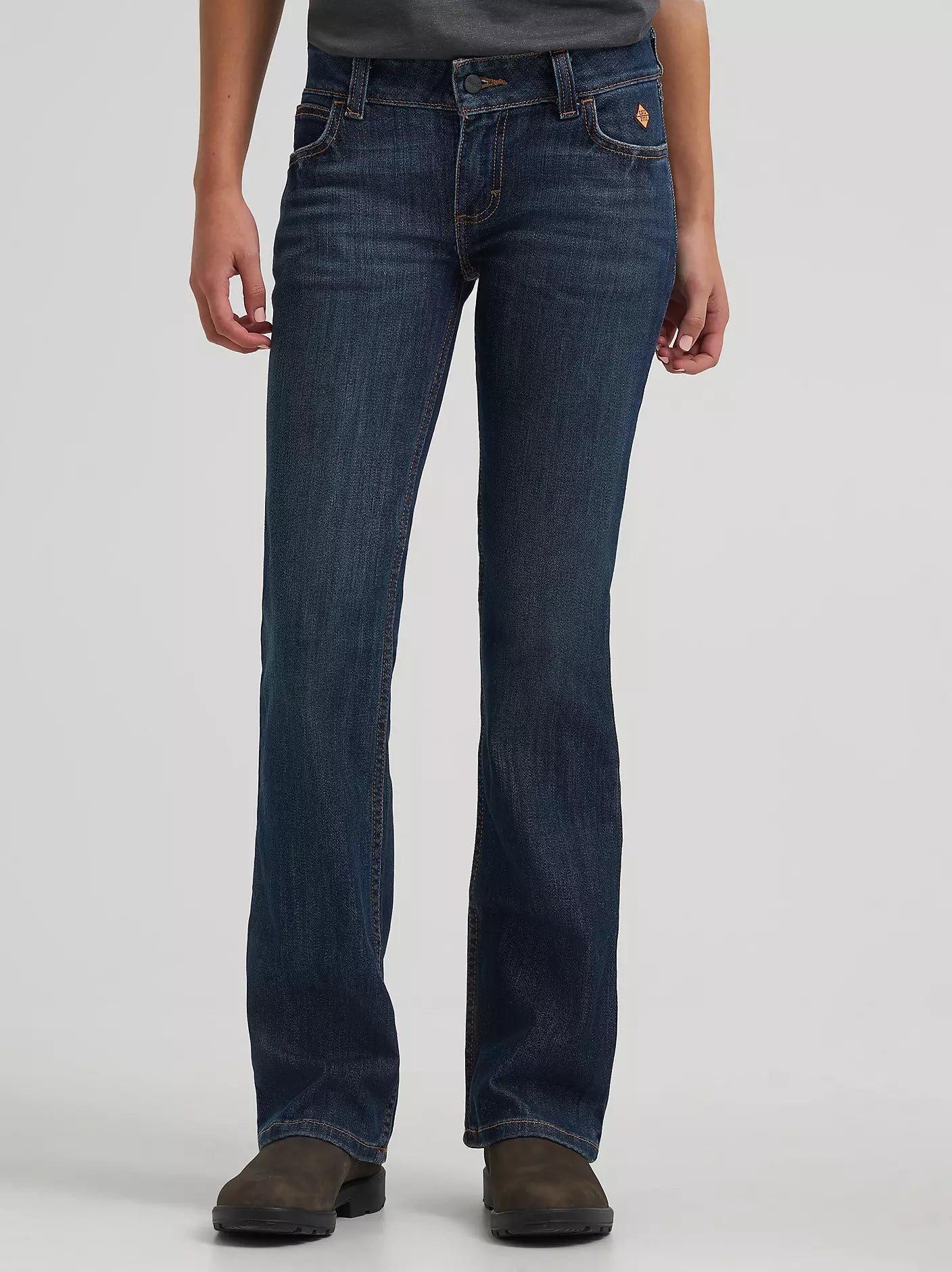 Woman wearing dark wash bootcut jeans and brown work boots, front view
