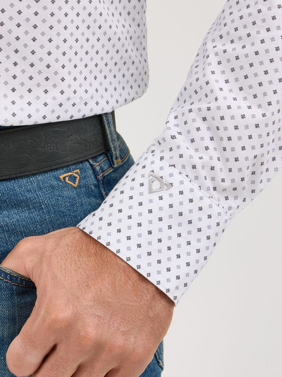 Close-up of man's hand in blue jeans pocket wearing grey patterned long sleeve shirt