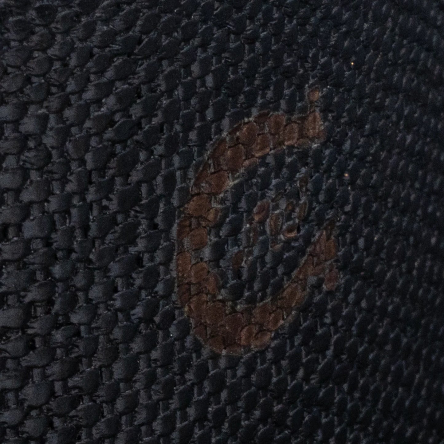 Close-up of a textured dark fabric with a brand logo.