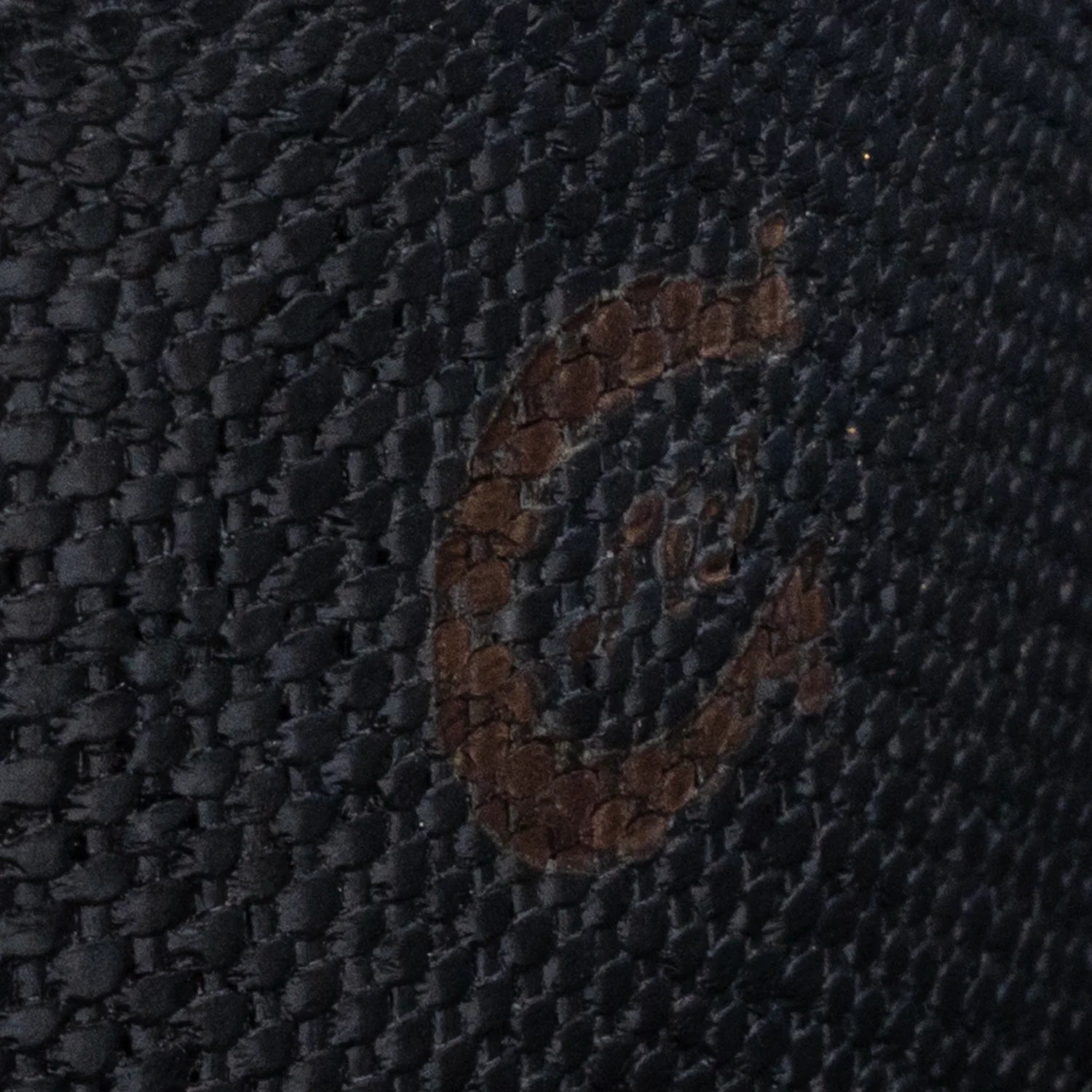 Close-up of a textured dark fabric with a brand logo.