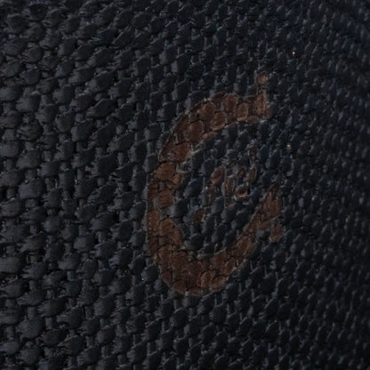 Close-up of a textured dark fabric with a brand logo.