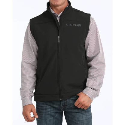 Person wearing a black Cinch vest over a striped shirt on a white background