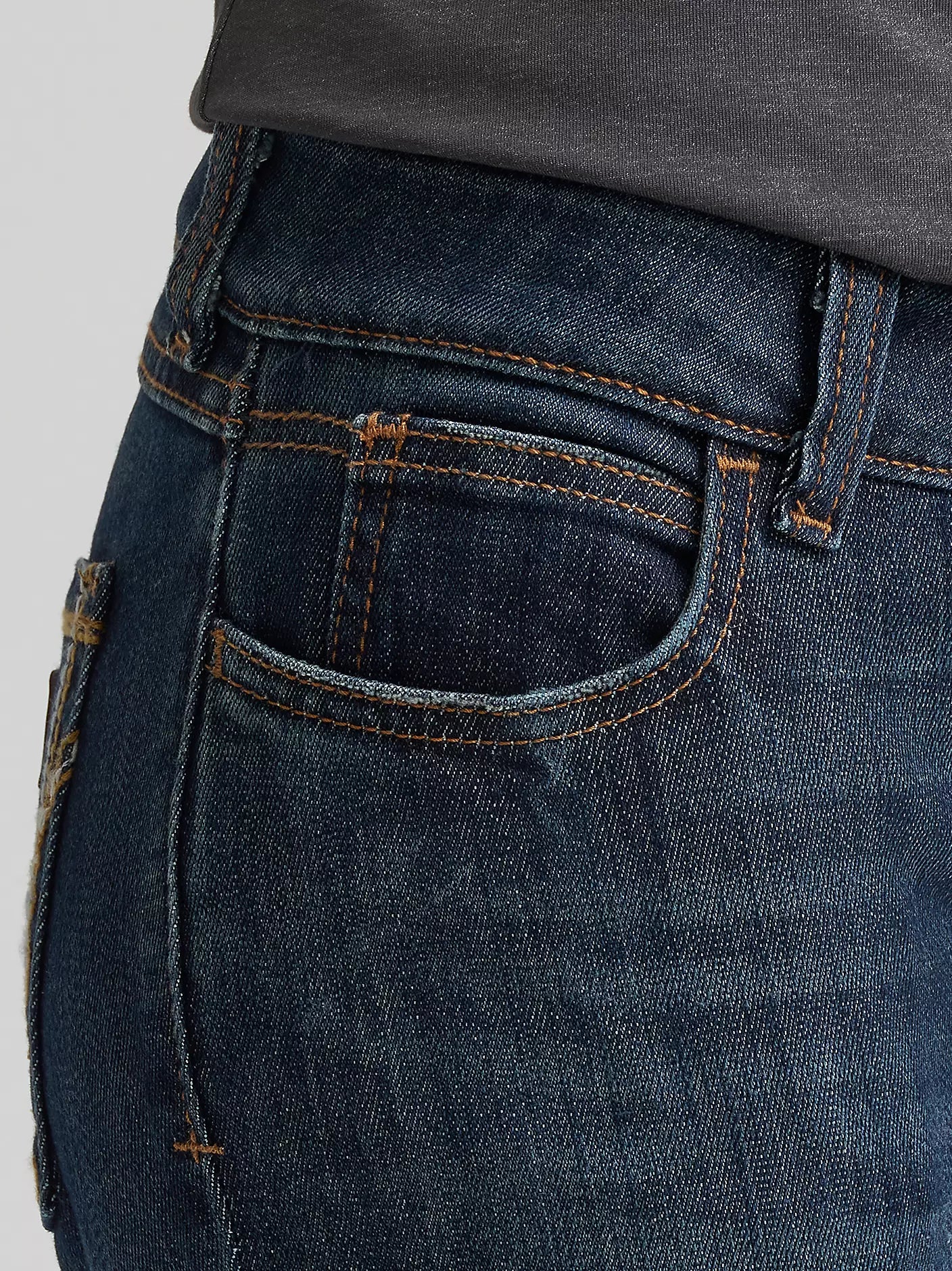 Close-up of dark blue denim jeans with orange stitching, back pocket detail