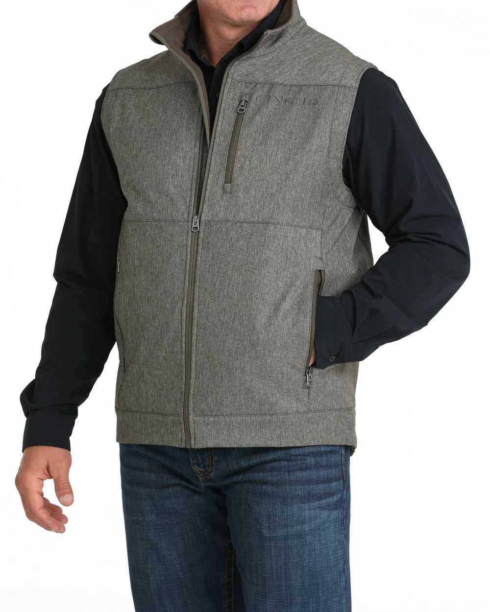 Men’s grey zip-up vest with high collar, chest pocket, and side pockets, styled over black shirt and jeans