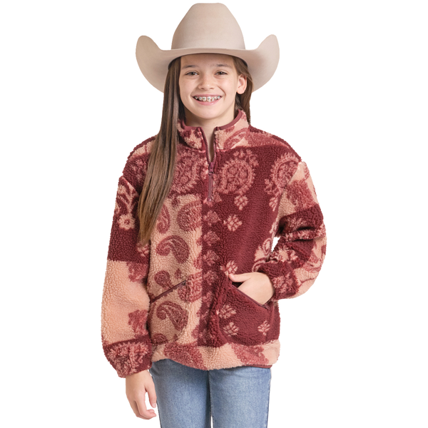 A young girl wearing a sherpa fleece quarter-zip jacket with a red and beige paisley pattern, a beige cowboy hat, and blue jeans, photographed against a solid white background.