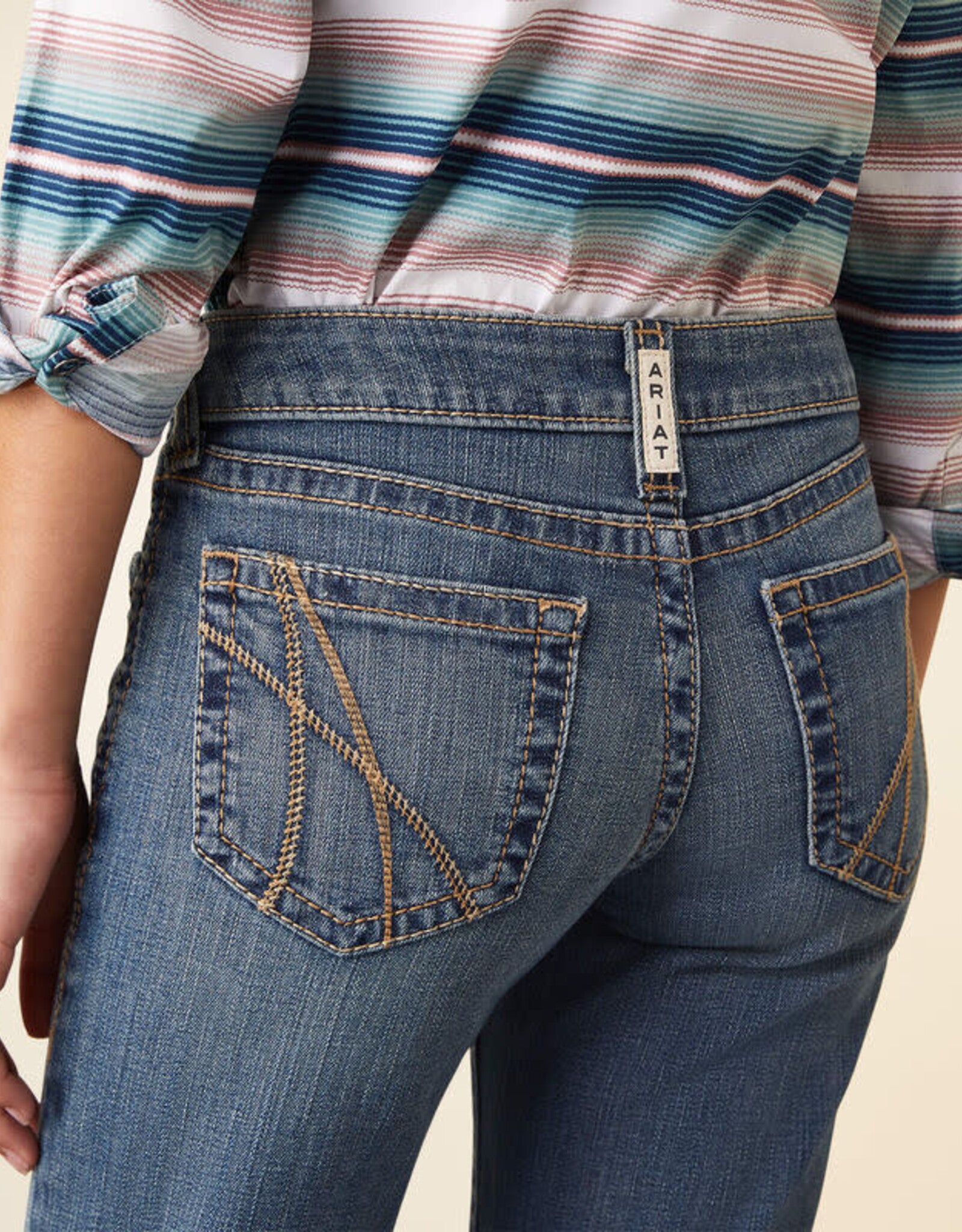 Close-up of woman's back wearing Ariat blue denim jeans with contrast stitching and striped shirt