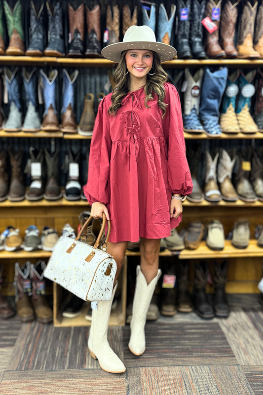 Woman in a red dress and white boots standing in front of a display of boots.