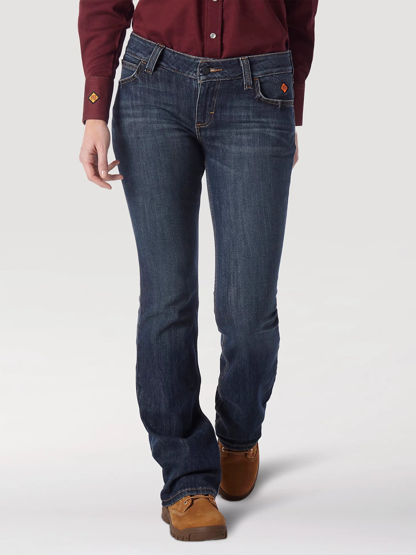 Woman wearing dark wash bootcut jeans, burgundy shirt, and brown work boots