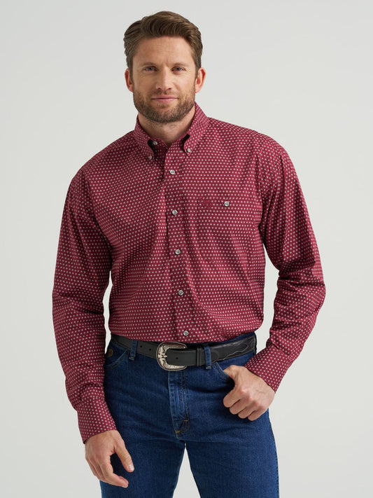 Man wearing a burgundy long sleeve button-down shirt with white dot pattern and blue jeans