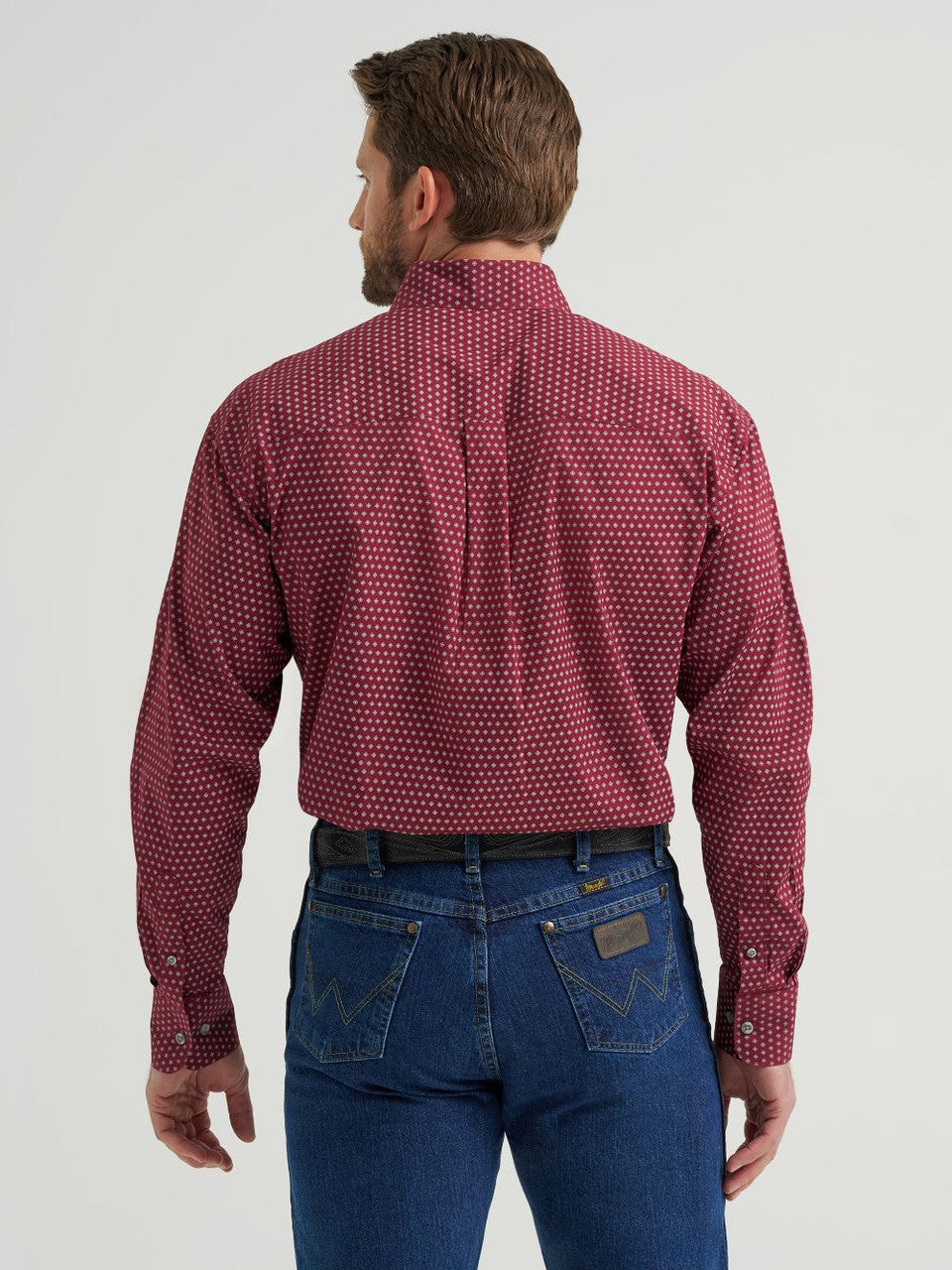 Man wearing burgundy polka dot long sleeve shirt and blue jeans, back view