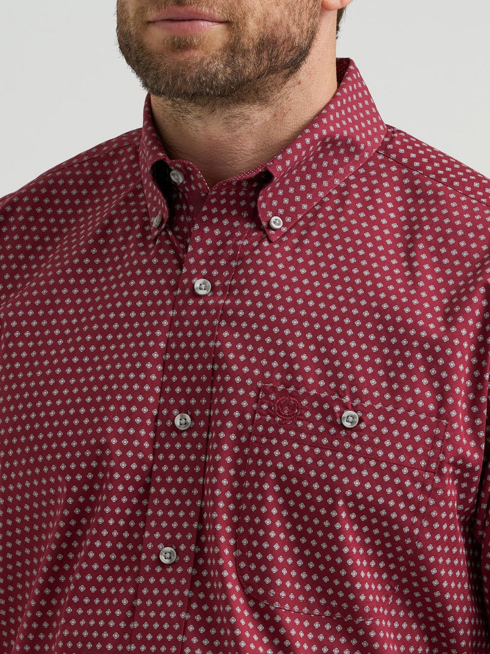 Close-up of a man wearing a burgundy dot pattern button-up men's shirt with pocket