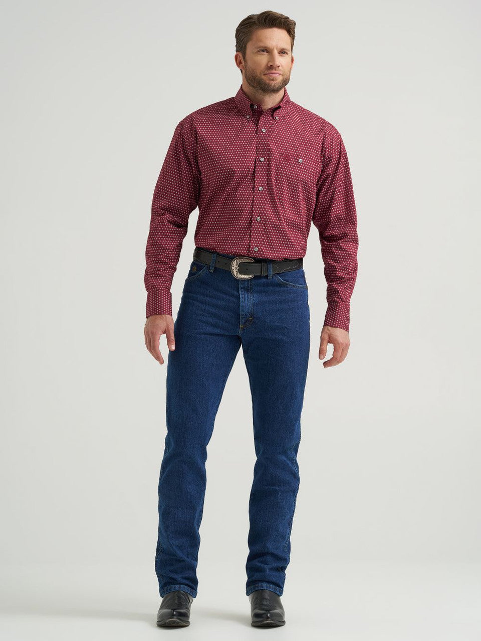 Man wearing burgundy dot long sleeve western shirt, blue jeans, and black boots