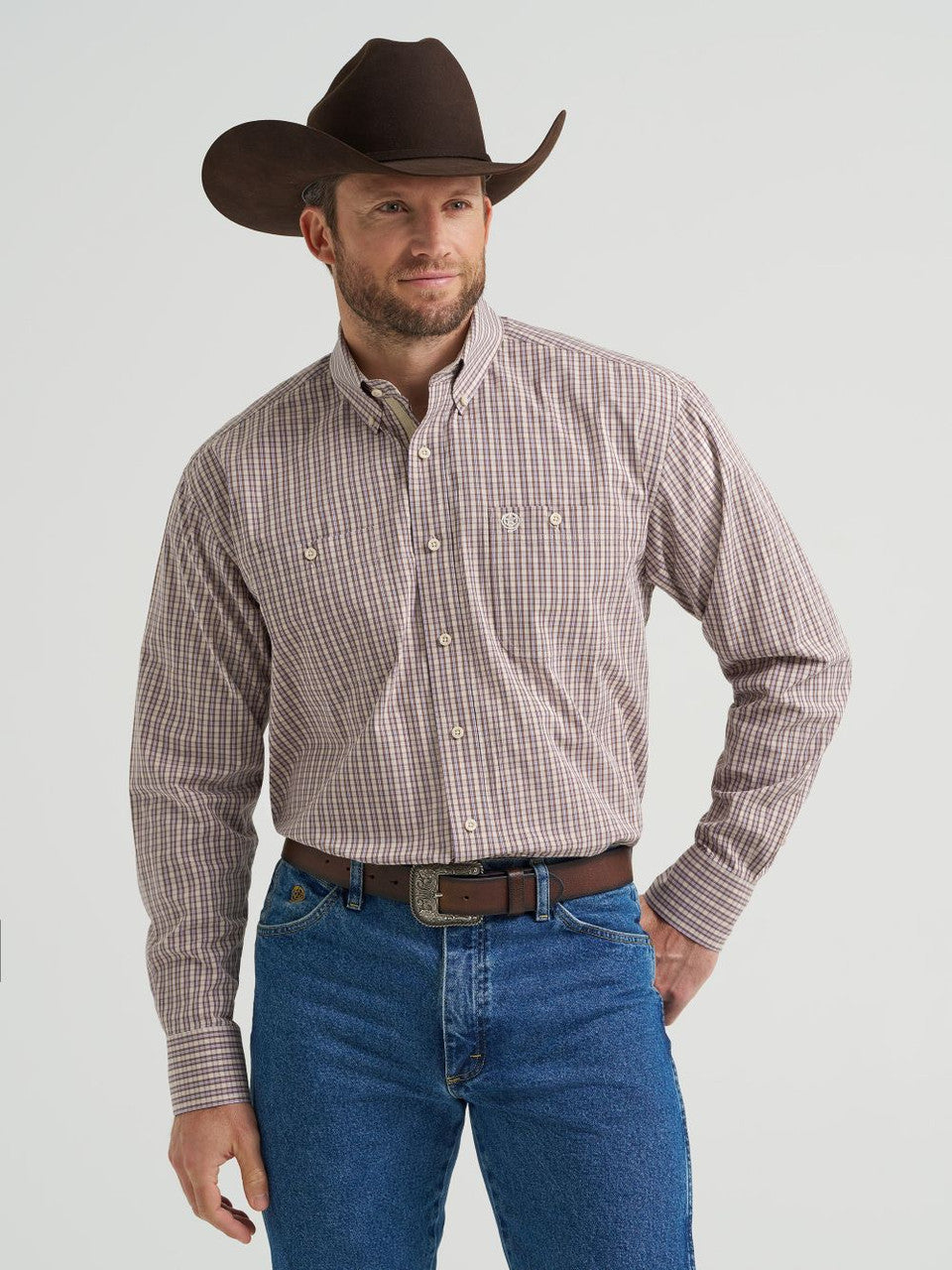 Man in cowboy hat wearing purple and tan plaid long sleeve western shirt and blue jeans