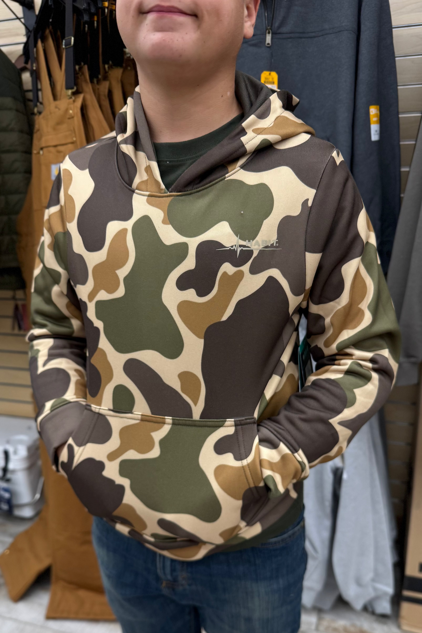 Man wearing green and brown camouflage hoodie in outdoor apparel store