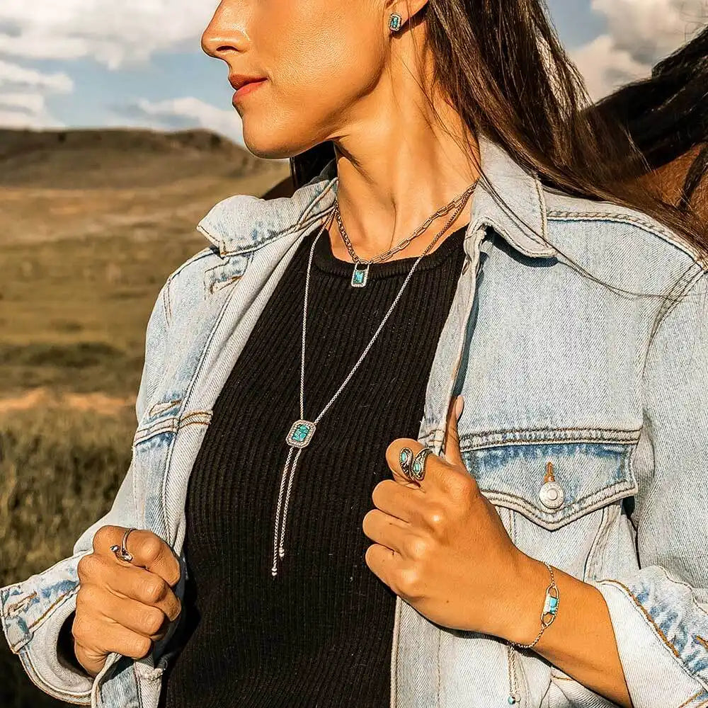 Woman outdoors wearing turquoise stone jewelry set, denim jacket, and black top
