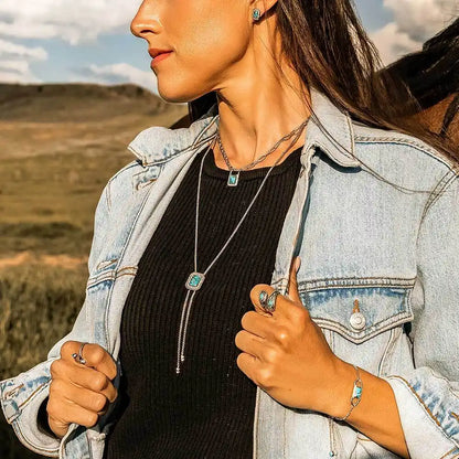 Woman outdoors wearing turquoise stone jewelry set, denim jacket, and black top