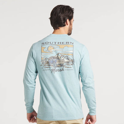Man wearing light blue long sleeve shirt with Southern Marsh graphic, mountains and SUV illustration