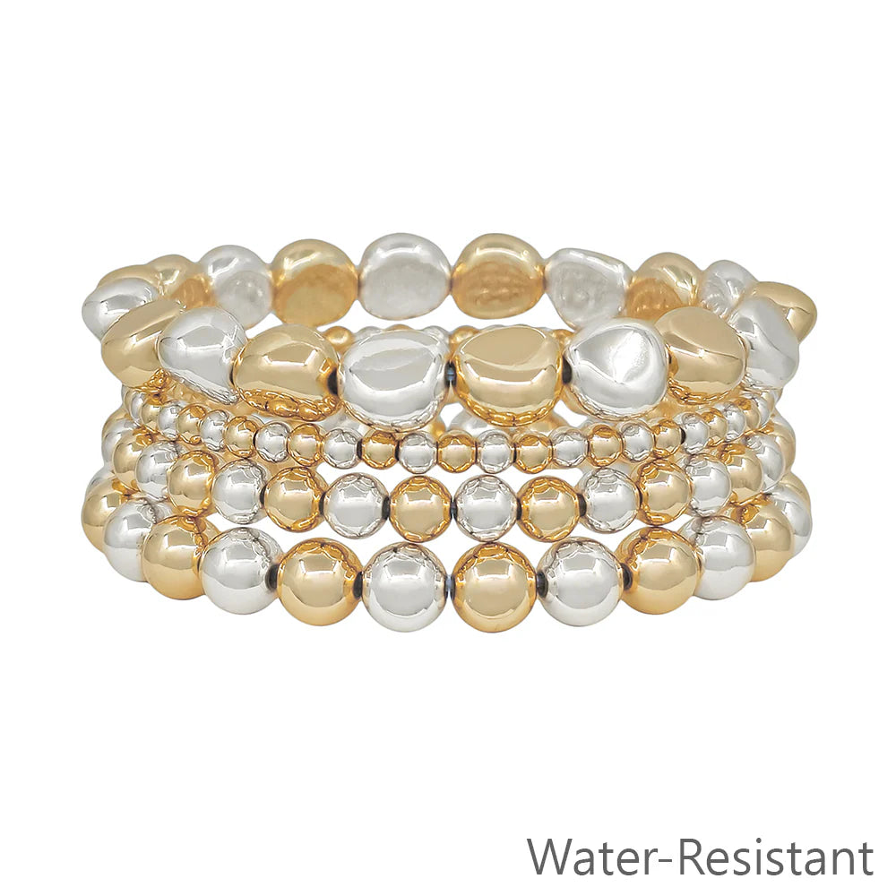 Stacked water-resistant gold and silver beaded stretch bracelets on white background