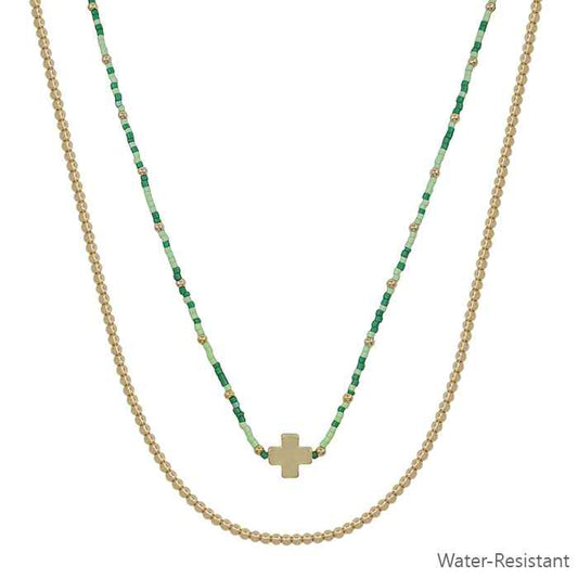 Two necklaces with green beaded chain and gold cross pendant on a white background.