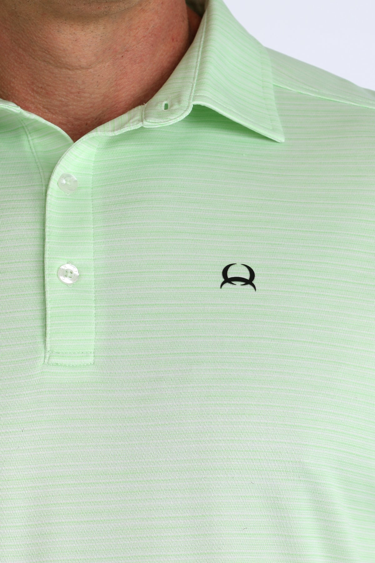 Close-up of a light green polo shirt with a small logo on the chest.