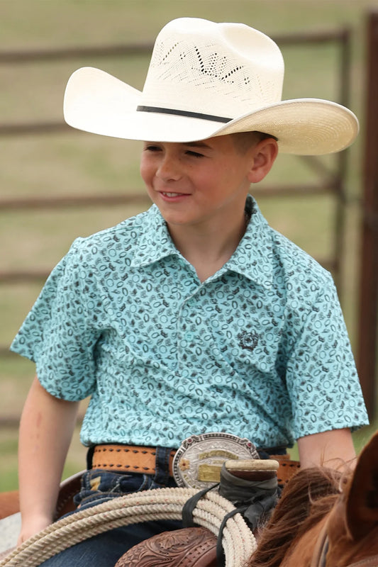 Young boy in a cowboy hat and patterned shirt sitting on a horse.