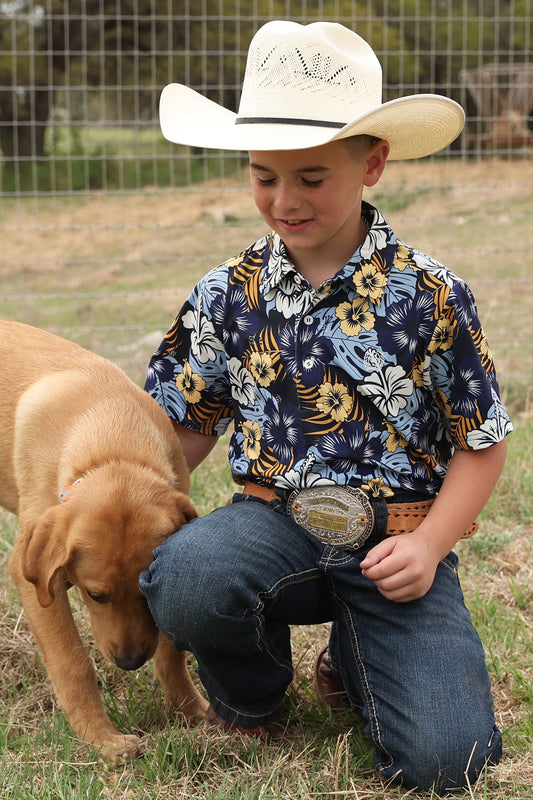 Child in cowboy hat and floral shirt with a dog outdoors