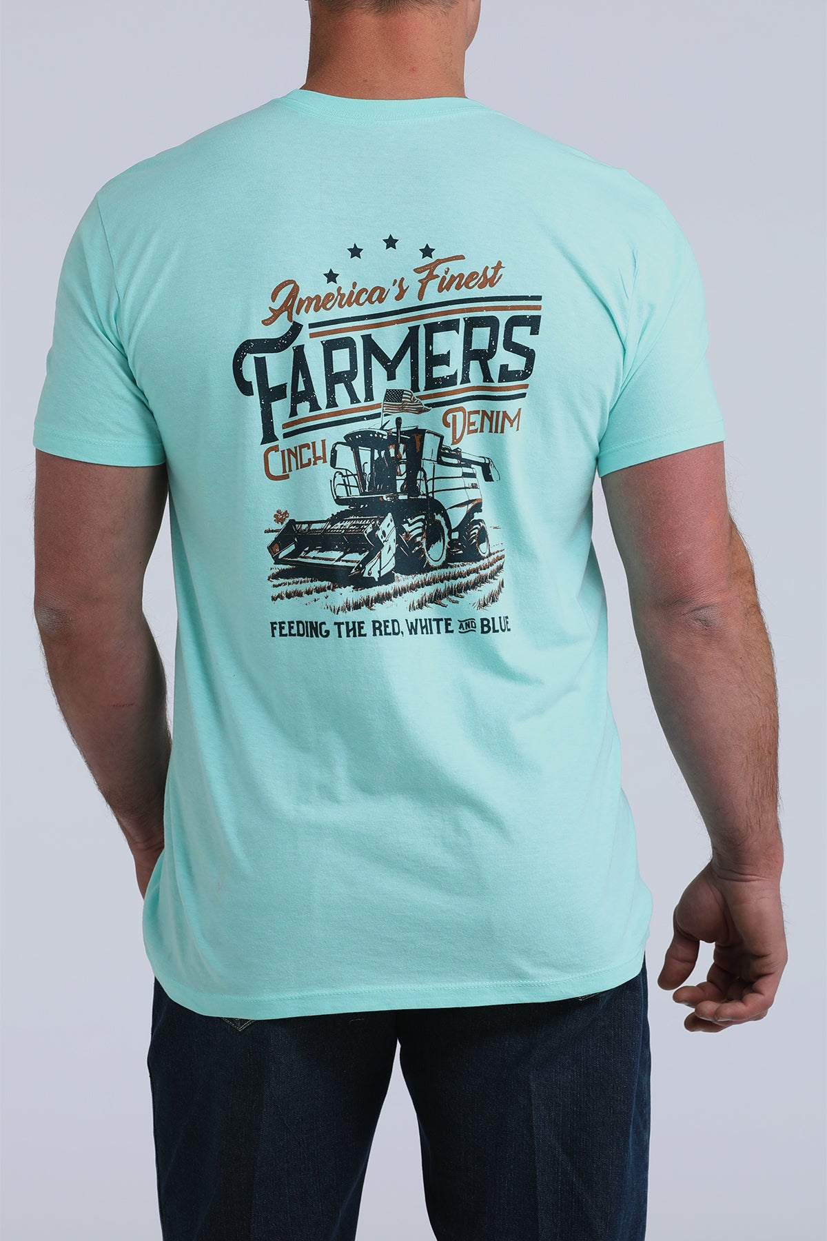 Man wearing light blue graphic T-shirt with farmer and tractor design, back view