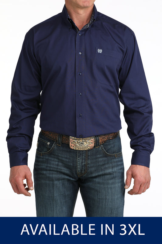 Man wearing a navy blue shirt and jeans with a decorative belt, on a white background.